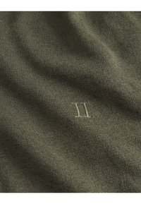 Olive green knit fabric featuring a subtle texture, with a small embroidered "II" in a lighter shade near the bottom right corner.