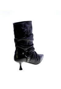 Stivale alla caviglia in pelle nera con design morbido, punta affilata e accento decorativo a catena. Dotato di un elegante tacco a stiletto.