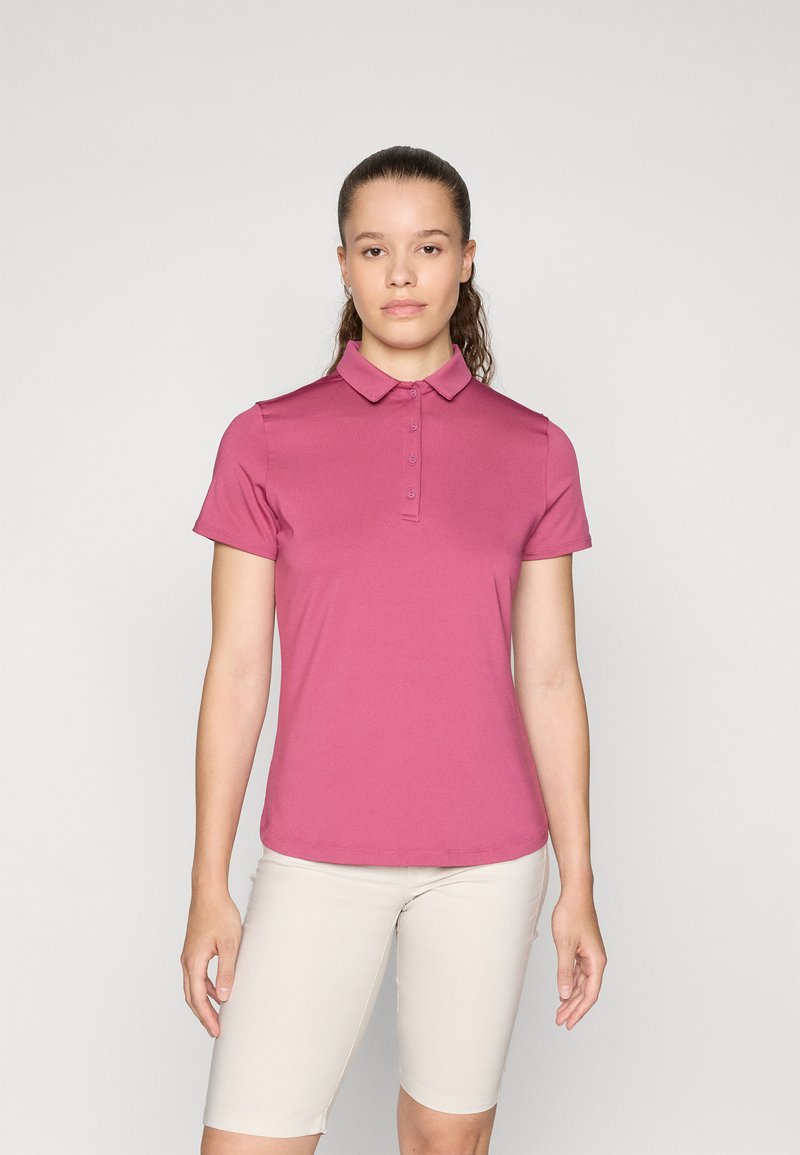 Pink polo skjorte med skræddersyet pasform, korte ærmer, ribbet krave og knaplukning; parret med lysebeige shorts. Glat stoftekstur.