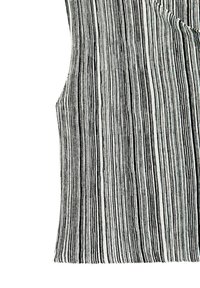 Randig svart och vit textil med vertikala linjer. Tyget har en texturerad, ribbad yta med varierande tjocklek i ränderna.