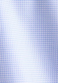 Gros plan sur un tissu bleu clair avec un motif en zigzag fin et répétitif créant un effet texturé en chevrons diagonaux.