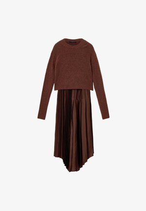 Pull court marron à manches longues associé à une jupe plissée marron avec un ourlet asymétrique et une texture lisse.