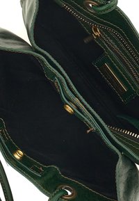 Borsa a mano verde in pelle con una texture morbida, dotata di un interno in tessuto nero, hardware dorato e una tasca con zip. Rifinita con bordi cuciti.