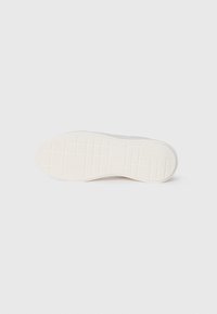 Witte sneakersole met een textuur van rubber. Voorzien van een reeks rechthoekige en vierkante patronen voor grip. Glad afgewerkt.