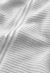 Tessuto bianco lavorato a maglia con strisce testurizzate orizzontali e verticali alternate, caratterizzato da una texture morbida e liscia. Leggero luccichio evidente.