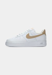 Białe sneakersy Nike Air Force 1 z beżowymi akcentami, skórzana cholewka, perforacje na palcach i teksturowana gumowa podeszwa.