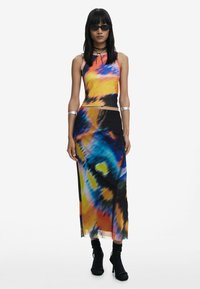 Colorful tie-dye dress featuring a fitted tank top and a flowing skirt. Made of a smooth fabric, with one side slit and layered accents.