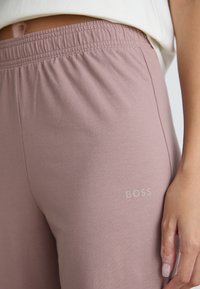 Pantalons de jogging rose clair en mélange de coton doux, avec une taille élastique et un logo "BOSS" subtil sur le côté inférieur.