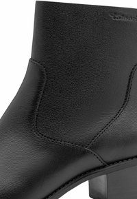 Botín de cuero negro hasta el tobillo con detalles de costura, textura suave, forma cónica y un tacón robusto. Sin herrajes ni adornos visibles.