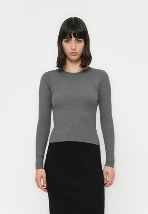 Grå, langermet tettsittende topp med ribbestuktur og rund hals. Kombinert med et svart blyantskjørt gir antrekket et rent, minimalistisk utseende.