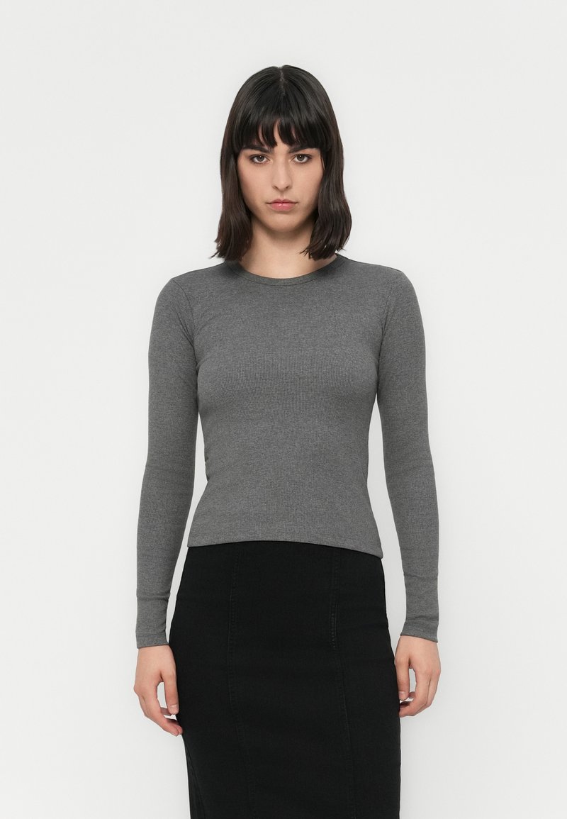 Gray, long-sleeve fitted top, ribbed texture, round neckline. Paired with a black pencil skirt, the outfit has a clean, minimalist look.