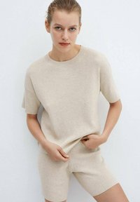 Beige ribbed knit short-sleeve top paired with matching shorts, featuring a round neckline and a soft texture. Simple, minimalistic design.