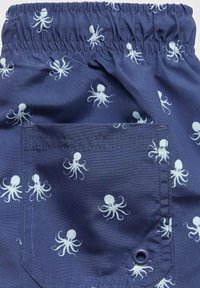 Námořnické modré látkové šortky s bílým vzorem chobotnice, vybavené elastickým pasem a malou zadní kapsou s kovovým kroužkem.