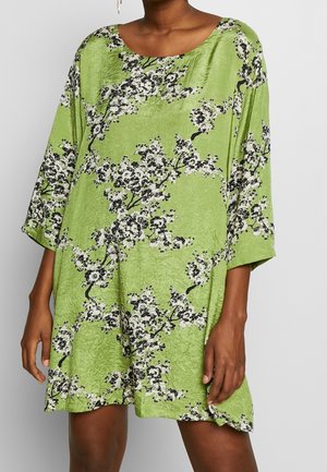 Robe ample verte avec des branches florales noires et blanches, dotée de manches trois-quarts et d'un col rond.
