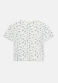 Λευκό crop top με κοντά μανίκια και μικρό μπλε λουλούδι σε ομοιόμορφα κατανεμημένο μοτίβο πάνω σε μονόχρωμο φόντο.