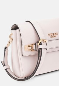 Helle rosa Lederhandtasche mit goldfarbenen Beschlägen, strukturiertem Design, abnehmbarem Schultergurt und geprägtem Logo auf der Vorderseite.