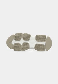 Semelle d'une chaussure de sport avec des patchs en caoutchouc beige pour la traction et une section centrale blanche sur un fond uni.