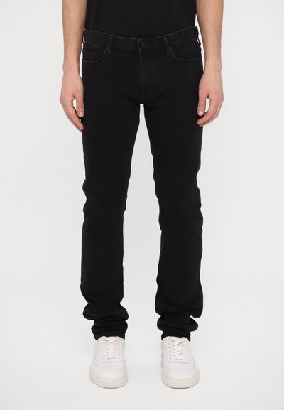 Zwart denim jeans met een slim fit, vijf-pocket ontwerp, subtiele stiksels, gecombineerd met witte sport sneakers.