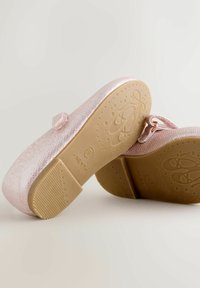 Lyserøde metalliske balletsko med tekstureret overflade, flad sål og en dekorativ rem med en lille spænde. Lysfarvet gummisål.