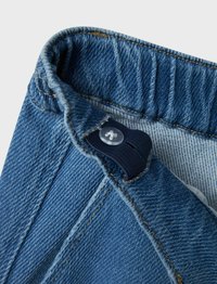 Denimjeans inuti, med en elastisk midja, knäppning med knapp, blått tyg med ljusa sömmar och en mjuk innersida.