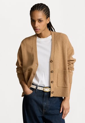 Ljusbrun cardigan i mjukt stickat material, med djup V-hals, knappframsida, ribbade ärmmuddar och en enda ficka. 
