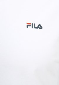 Weißes Baumwoll-T-Shirt mit kleinem schwarzen und roten FILA-Logo auf der Brust, mit einer glatten Textur und klassischem Rundhalsausschnitt.