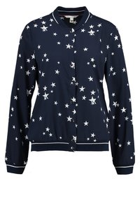 Marinblå bomberjacka med vit stjärnprint, långa ärmar, ribbade manschetter och nederkant samt knappstängning framtill. Mjuk tyg med slät textur.