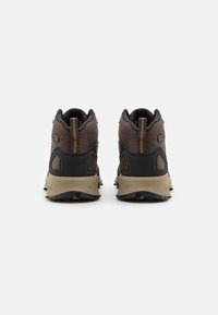 Zapatos de senderismo marrones con parte superior de malla, acentos oscuros y suela texturizada. Cuenta con un lazo trasero y un talón reforzado para mayor durabilidad.