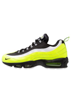 Neongul, sort og hvid atletiksneaker med synlige luftsåler, mærkede snørebånd og træksløjfe ved hælen.