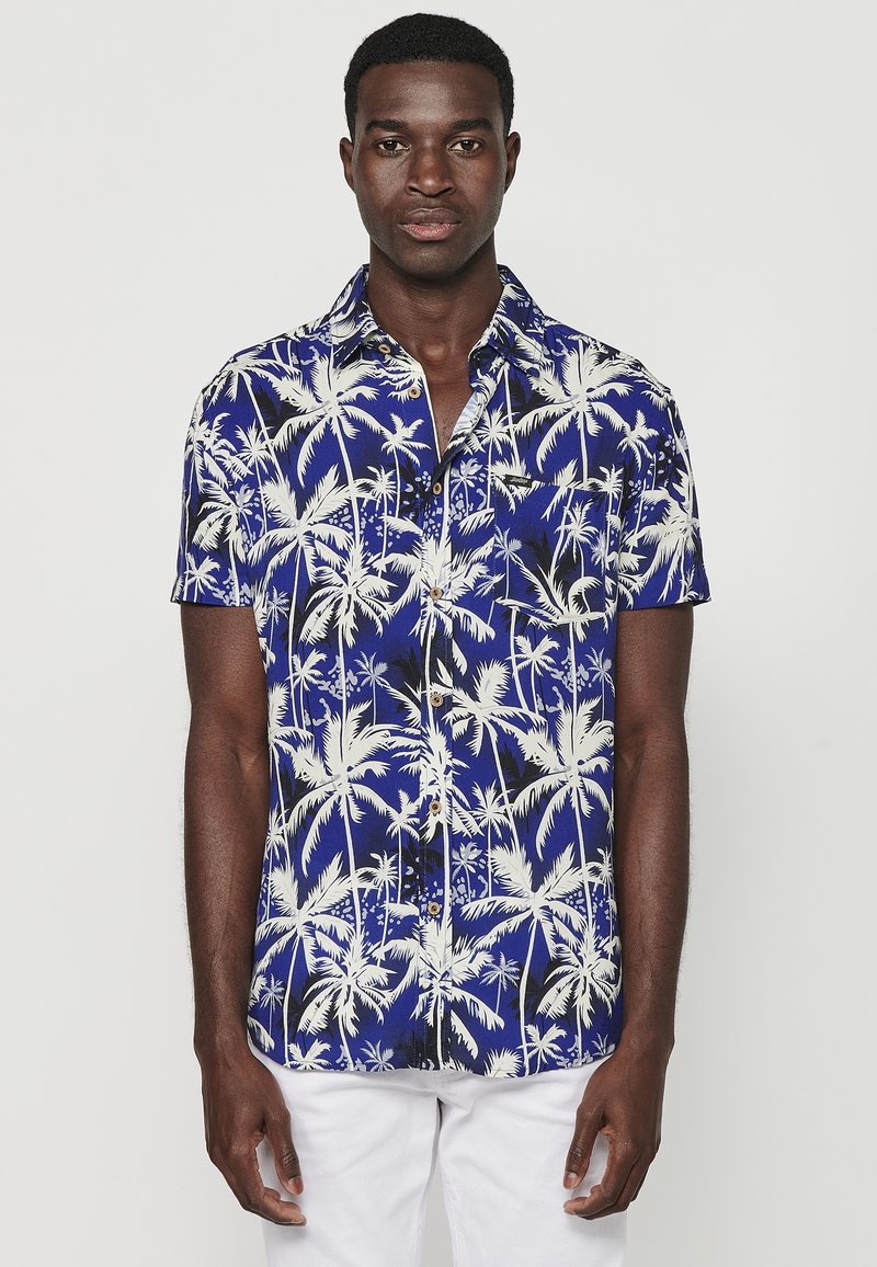 Camicia a maniche corte con bottoni, di colore blu e motivo palme bianche, con colletto classico e una tasca sul petto.