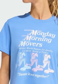 Blå bomulds T-shirt med korte ærmer. Foran har den hvid og pastel trykt tekst samt silhuetter af løbere. Rund halsudskæring.