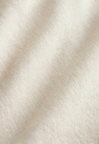 Material fin, de culoare bej deschis, cu o textură ușor lucioasă, evidențiind tipare de țesătură subtile și un aspect moale și fluid.