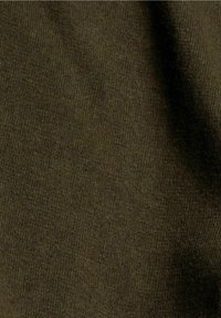 Gros plan sur un tissu tricoté vert olive foncé avec une texture fine et uniforme et des plis subtils.