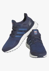 Ténis de corrida em azul-marinho com um superior em malha respirável, acentos texturizados e tr�ês riscas azuis. Apresenta uma sola branca almofadada e detalhes estampados.