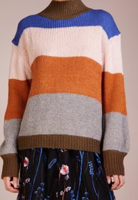 Flerfärgad stickad tröja med ribbad polokrage och långa ärmar. Ränder i rosa, orange, blått, grått och brunt. Mjuk struktur.