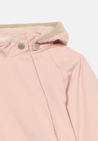 Ελαφρώς ροζ μπουφάν με μπεζ ριμπ ύφασμα στον γιακά, πατήματα με κουμπιά στη κουκούλα και επένδυση από φλις που διακρίνεται μέσα στον γιακά.