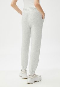 Pantalones de chándal gris claro, confeccionados en una suave mezcla de algodón, que cuentan con una cintura elástica, bolsillos laterales y puños acanalados en los tobillos.