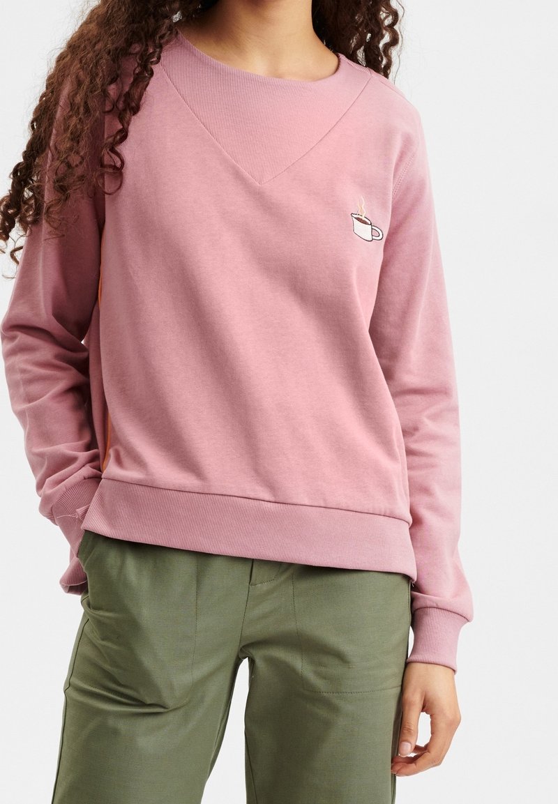 Rosa sweatshirt med en texturerad v-ringning, ribbade ärmslut och nederkant. Har en liten broderad koppgrafik på bröstet. Matchar med gröna byxor.