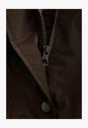 Giacca marrone con chiusura a zip e dettaglio a bottone. Il tessuto appare liscio con una leggera lucentezza. La zip e il bottone sono di colore grigio scuro e verde.