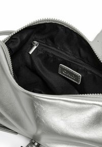 Sac à main argenté ouvert révélant un intérieur en tissu noir avec une poche zippée et une étiquette cousue portant l'inscription "ONLY".