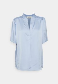 Blusa de seda azul claro, de mangas curtas. Apresenta um colarinho regular e um decote em V com pregas subtis nos ombros.