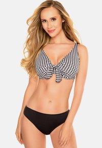 Schwarzes und weißes Hahnentrittmuster-Bikini-Oberteil mit Knoten vorne, kombiniert mit einfarbigen schwarzen Bikini-Unterteilen. Glattes Material, dreieckige Form.