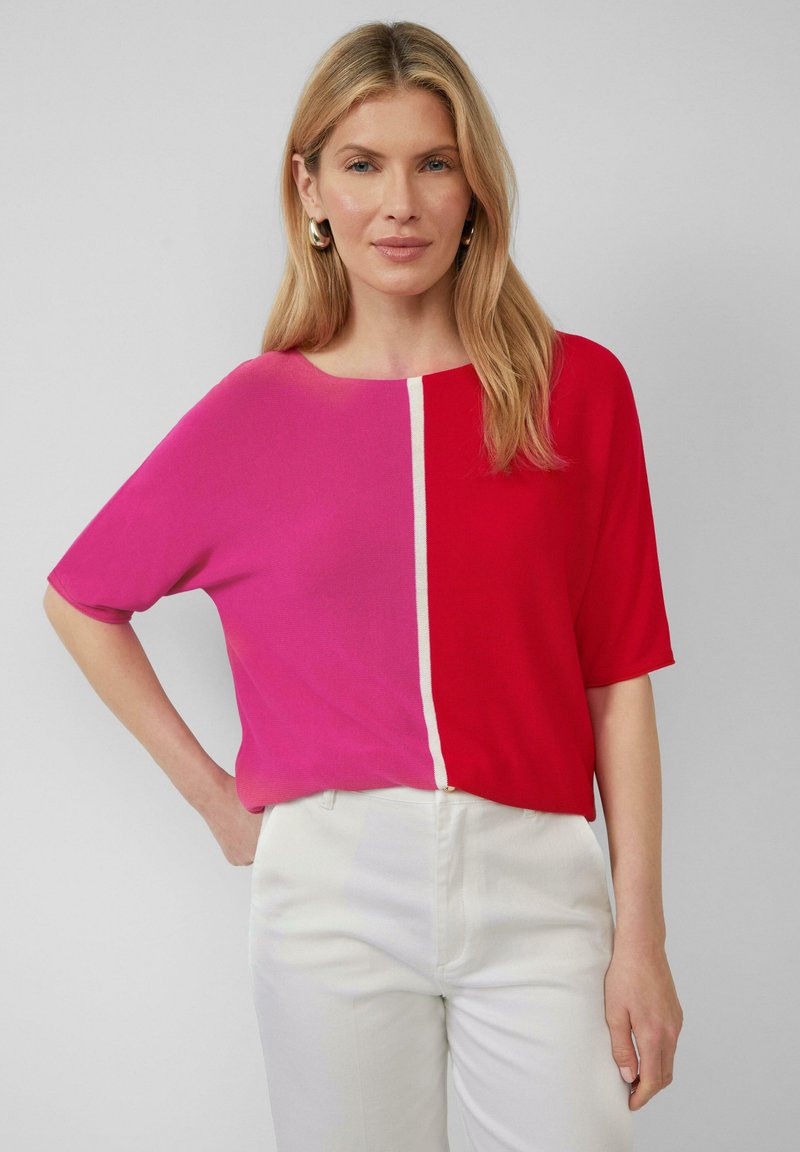 Korte mouw top met een gesplitst ontwerp in roze en rood, met een contrasterende witte naad. De stof lijkt lichtgewicht met een gladde textuur.