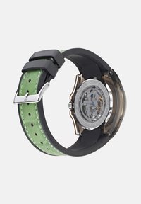 Orologio automatico con fondo cassa trasparente, cinturino in silicone verde, hardware argentato e accenti neri. Resistente all'acqua fino a 30 metri.