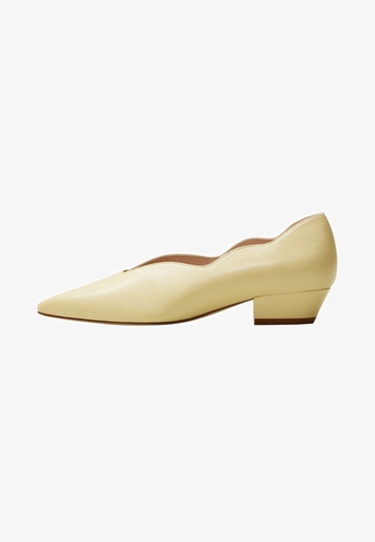 Chaussure pour femme en cuir beige à talon bas, bout pointu et bord festonné le long de la ligne supérieure, vue de profil.