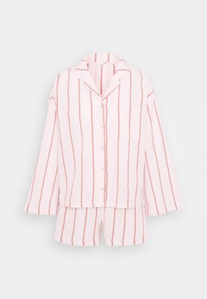 Pigiama a righe rosa composto da un tessuto leggero, con una camicia con bottoni e tasca sul petto e pantaloni corti coordinati.