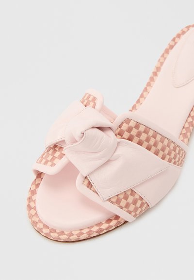 Ανοιχτό ροζ σανδάλι τύπου σαγιονάρα με υφαντό καρό περίγραμμα και φαρδιά δερμάτινη λωρίδα με μεγάλο κόμπο στην περιοχή των δακτύλων.