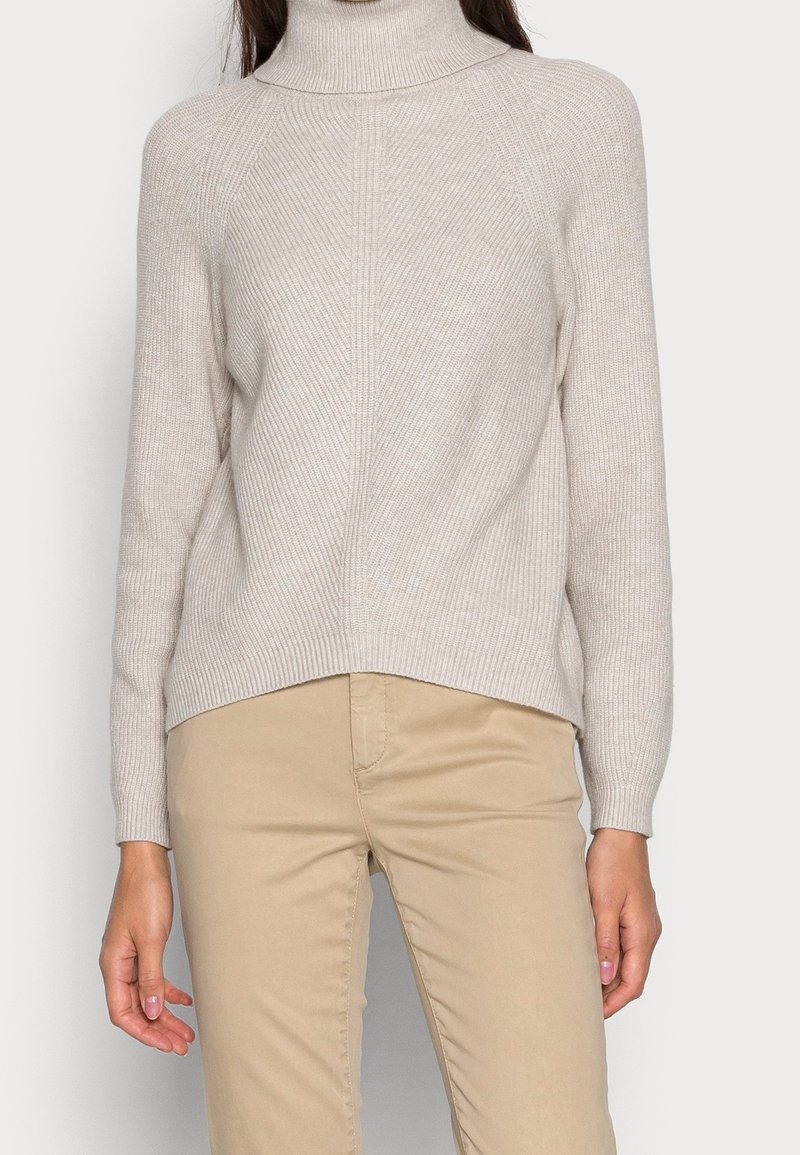 Maglione pesco chiaro a collo alto con texture a coste e maniche lunghe. Caratterizzato da una vestibilità rilassata e un design con orlo leggermente asimmetrico.
