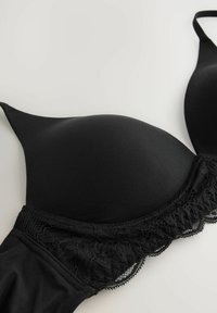 Schwarzer BH mit glatten, geformten Cups und einer Spitzenborte am unteren Rand sowie verstellbaren Trägern, aus weichem Stoff gefertigt.