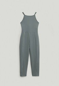 Une combinaison sans manches grise avec de fines bretelles, un corsage ajusté et des pantalons droits fuselés, posée à plat sur un fond clair.